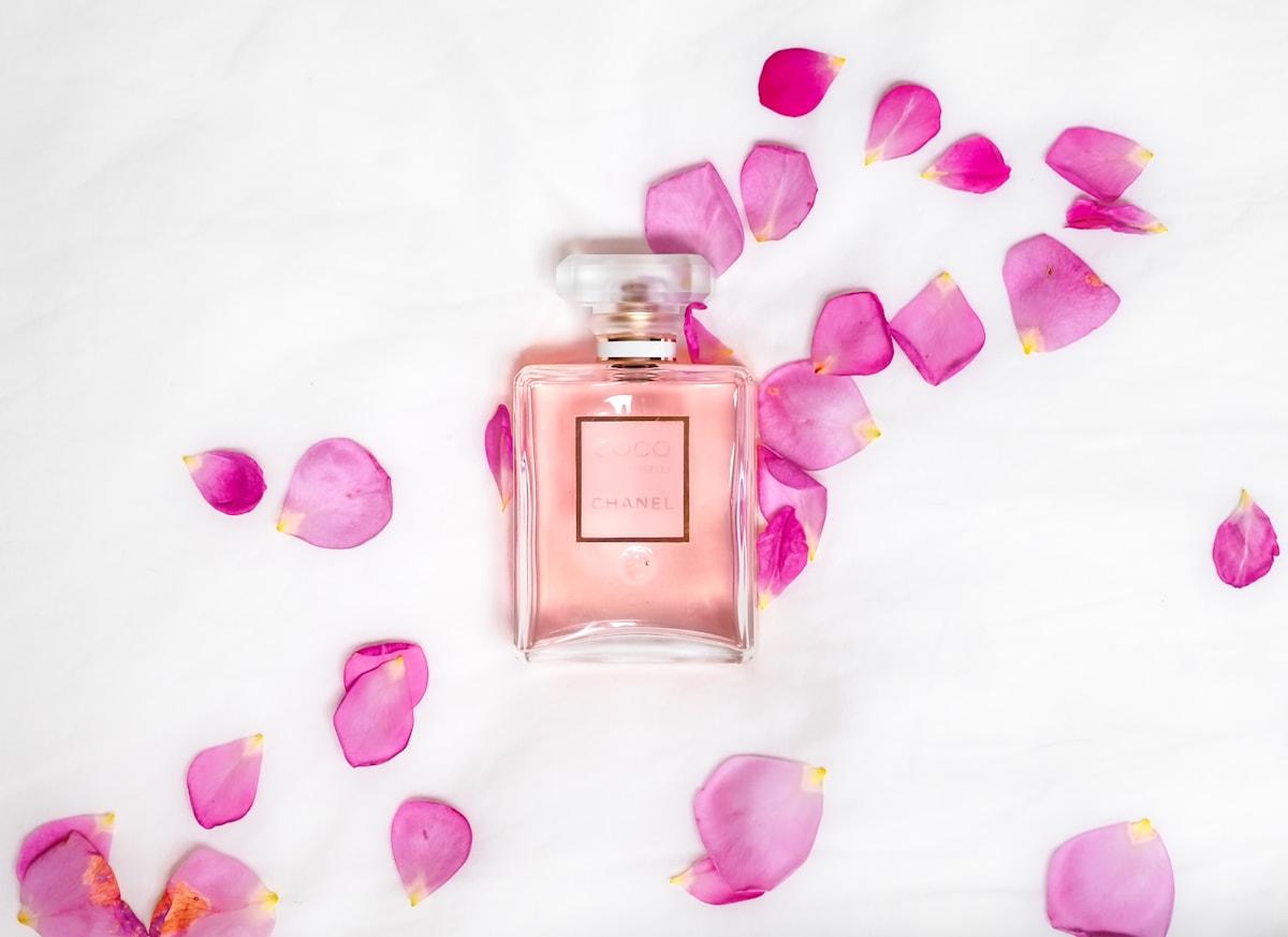 Perfume bottle with pink rose petals flatlay